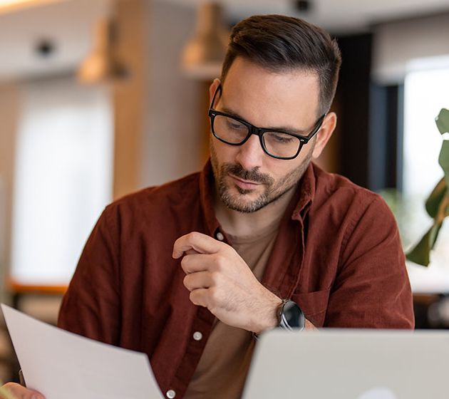 A business owner looking over a paper invoice at his desk