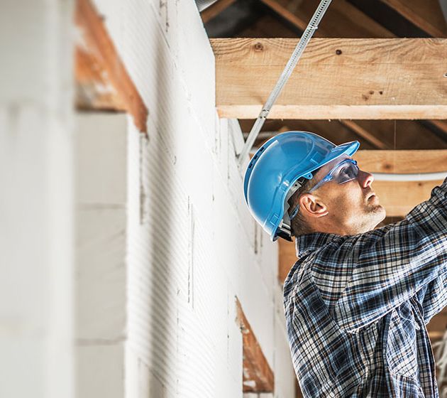 A contractor in a hard hat running cable in a new construction building