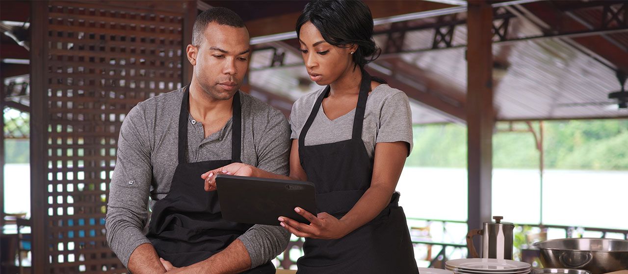 Restaurant employees looking over sales reporting tools from North