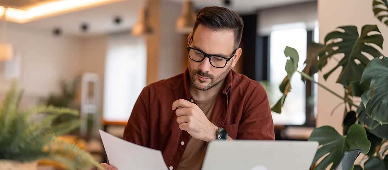 A business owner looking over a paper invoice at his desk