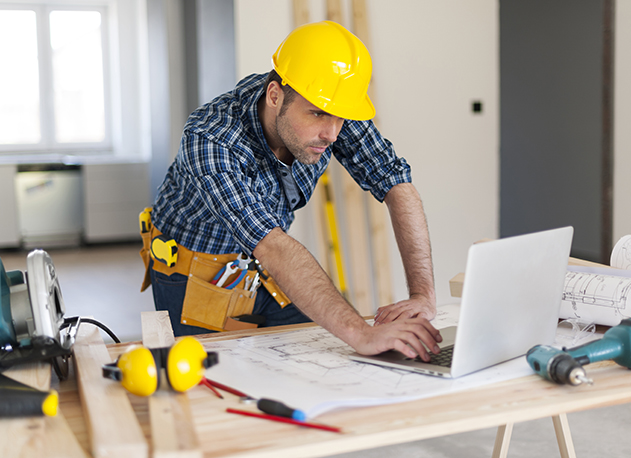 A contractor managing employees on a laptop while on a jobsite