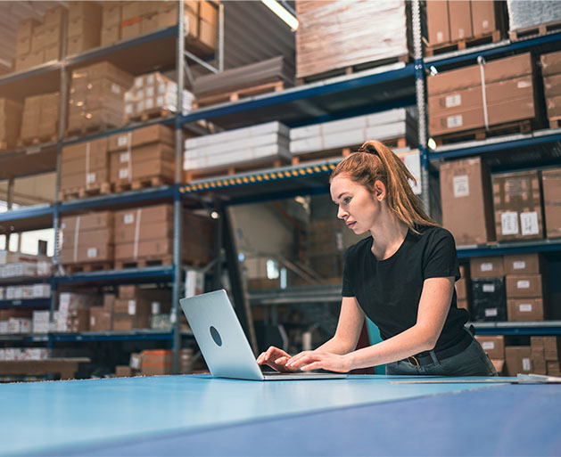 A contractor managing inventory in a warehouse on a laptop