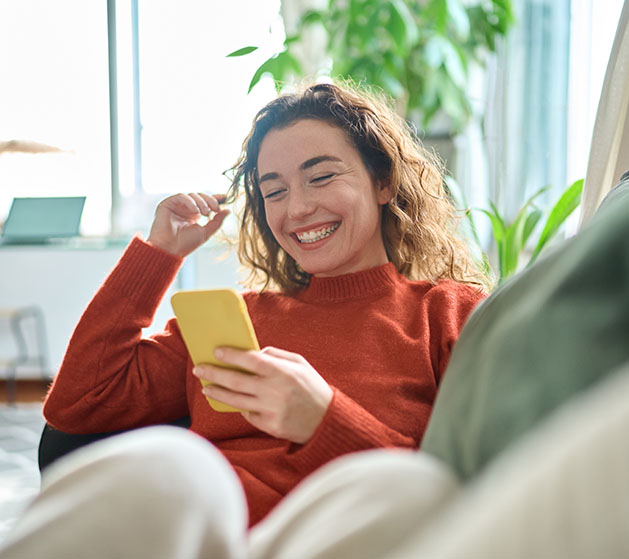 A woman smiling at her phone looking at the all the online rewards she's getting thanks to North POS systems