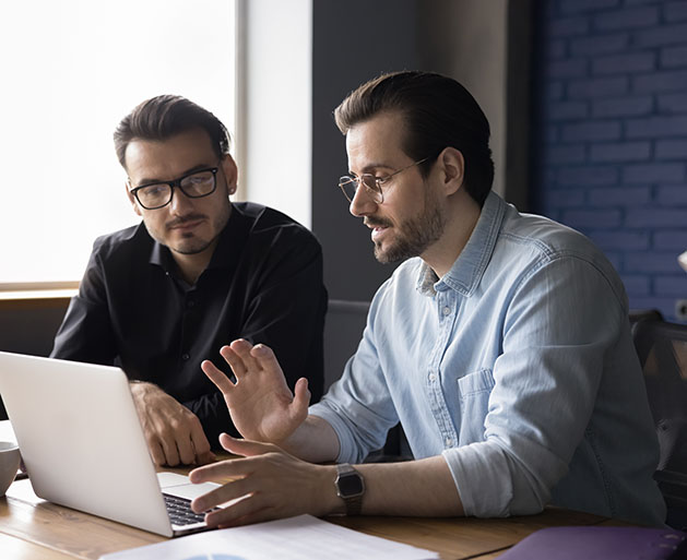 Two men at laptops discussing North's intergraded payment processing systems